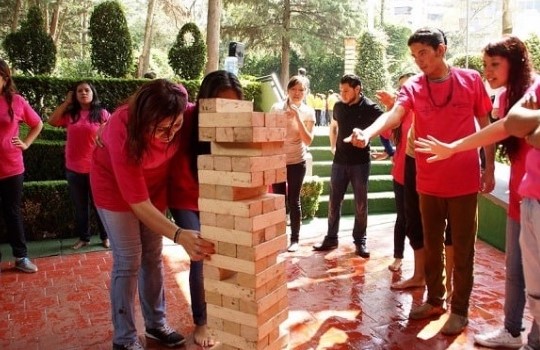 A group of people playing an oversized Jenga game outdoors.